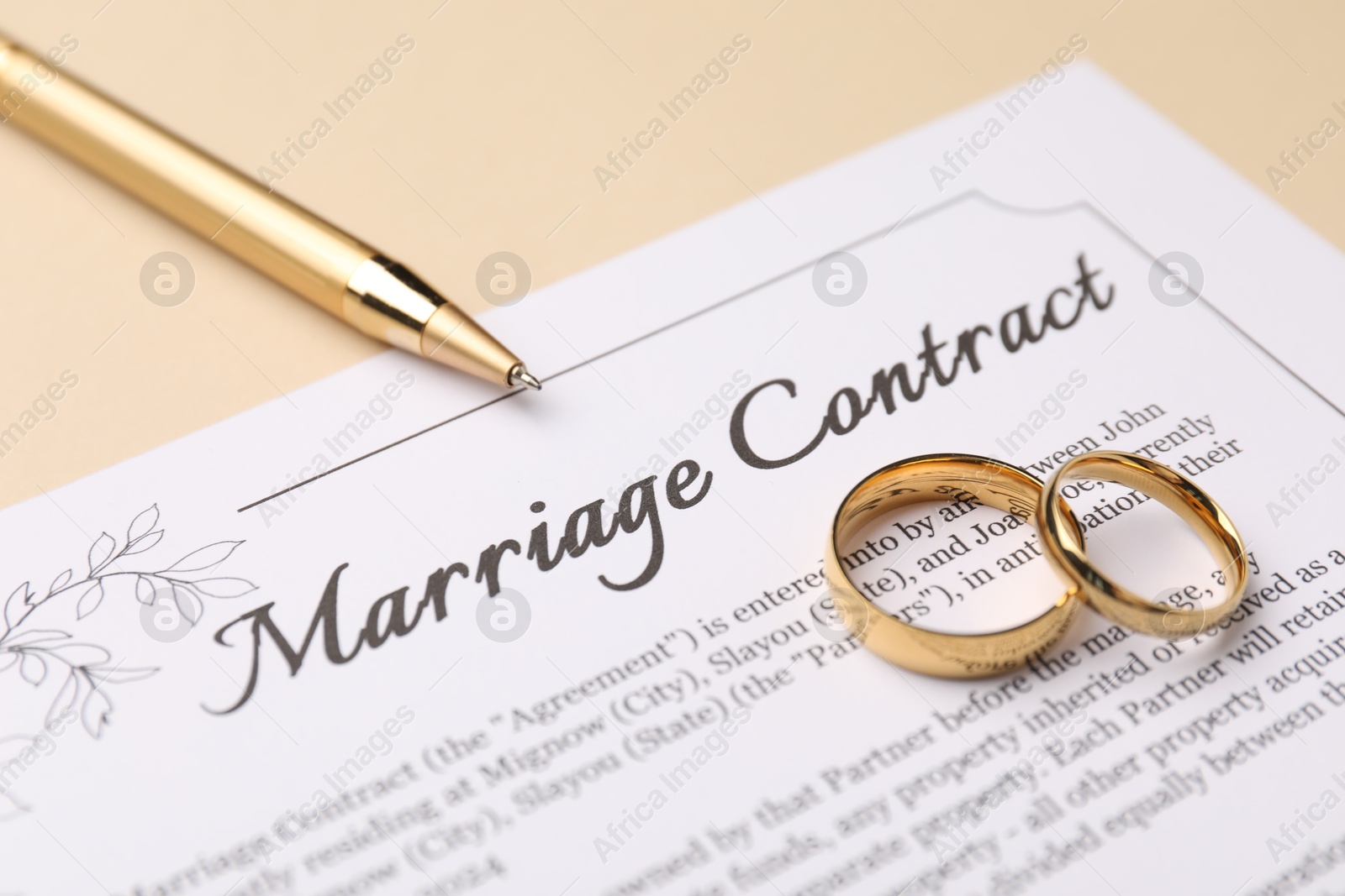 Photo of Marriage contract, pen and golden rings on beige background, closeup