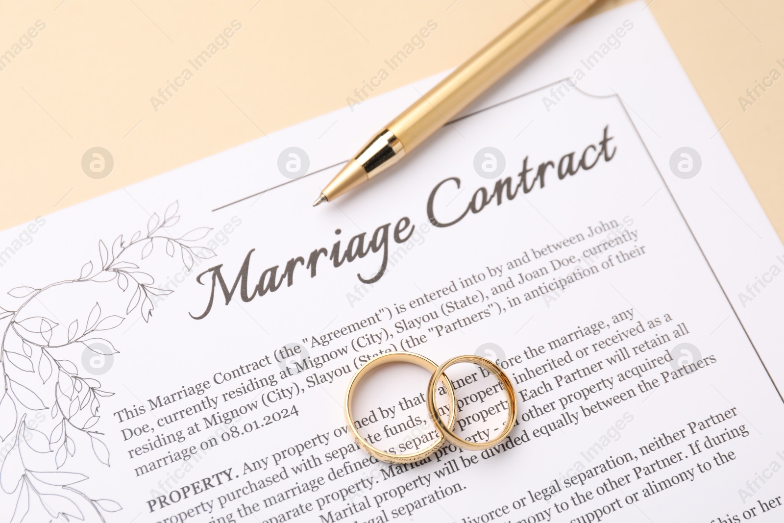 Photo of Marriage contract, pen and golden rings on beige background, top view