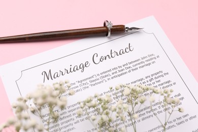 Photo of Marriage contract, flowers, pen and ring on pink background, above view