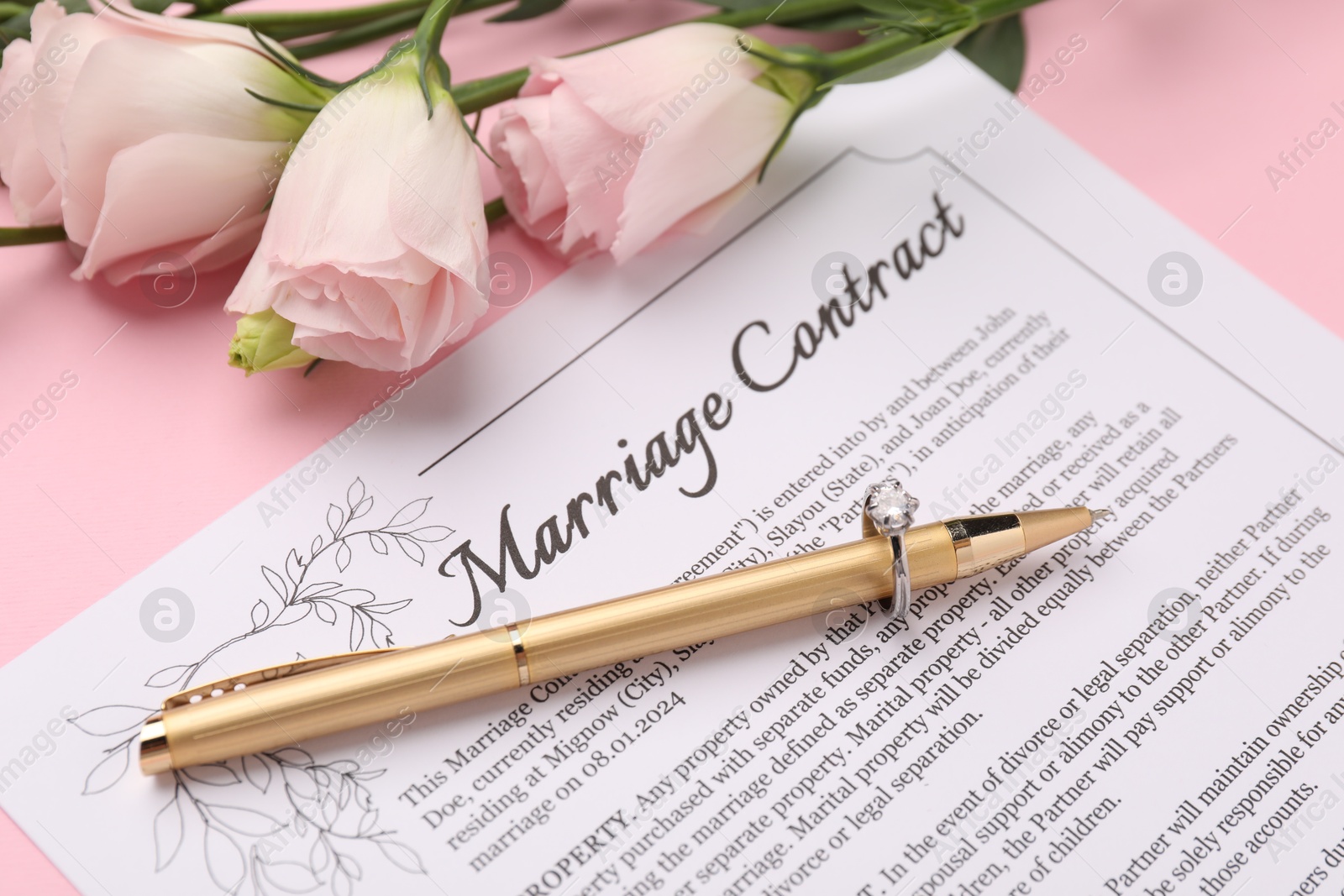 Photo of Marriage contract, flowers, pen and ring on pink background, closeup