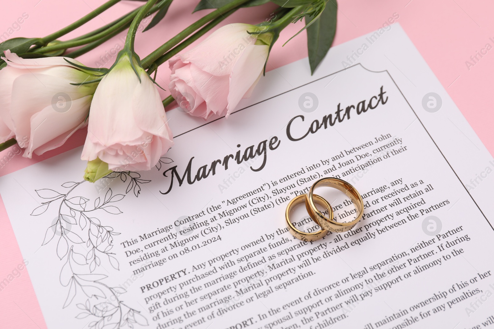 Photo of Marriage contract, flowers and golden rings on pink background, closeup