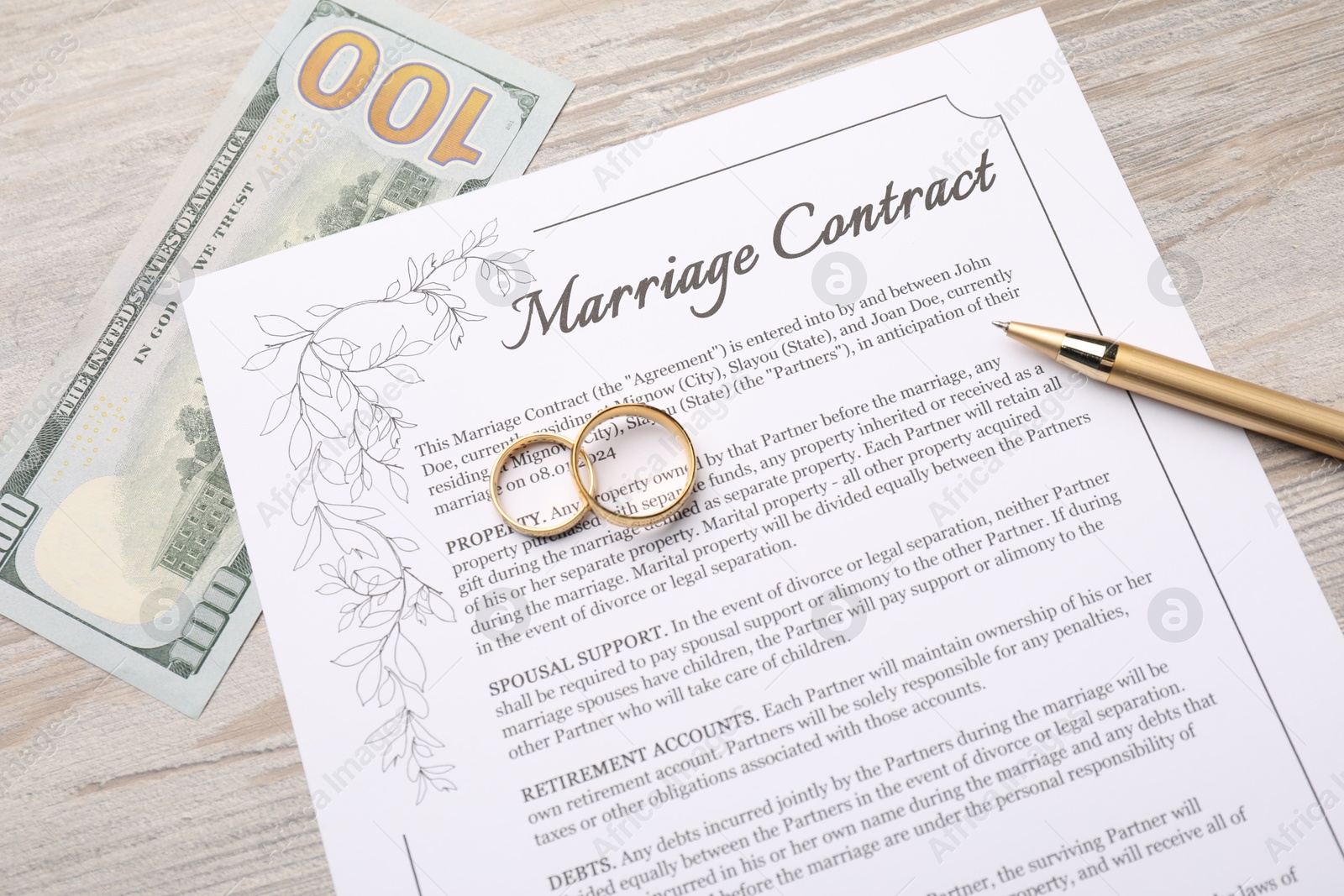 Photo of Marriage contract, pen, dollar bill and golden rings on light wooden table, top view