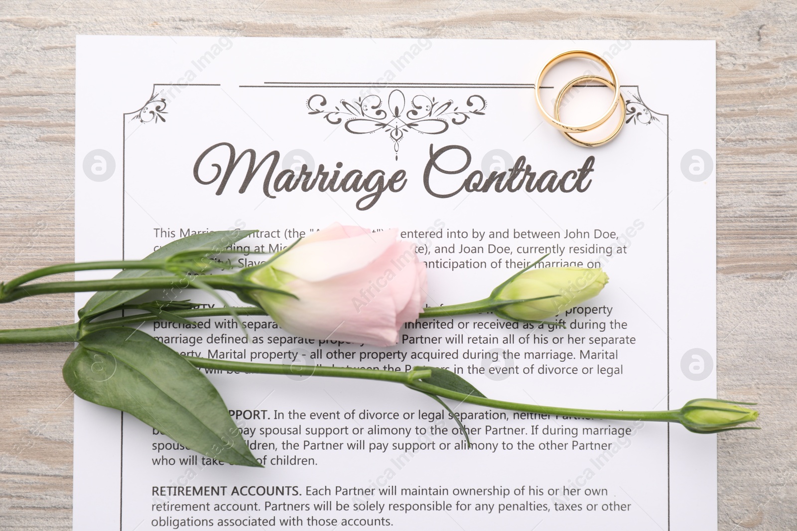 Photo of Marriage contract, flowers and golden rings on wooden table, top view