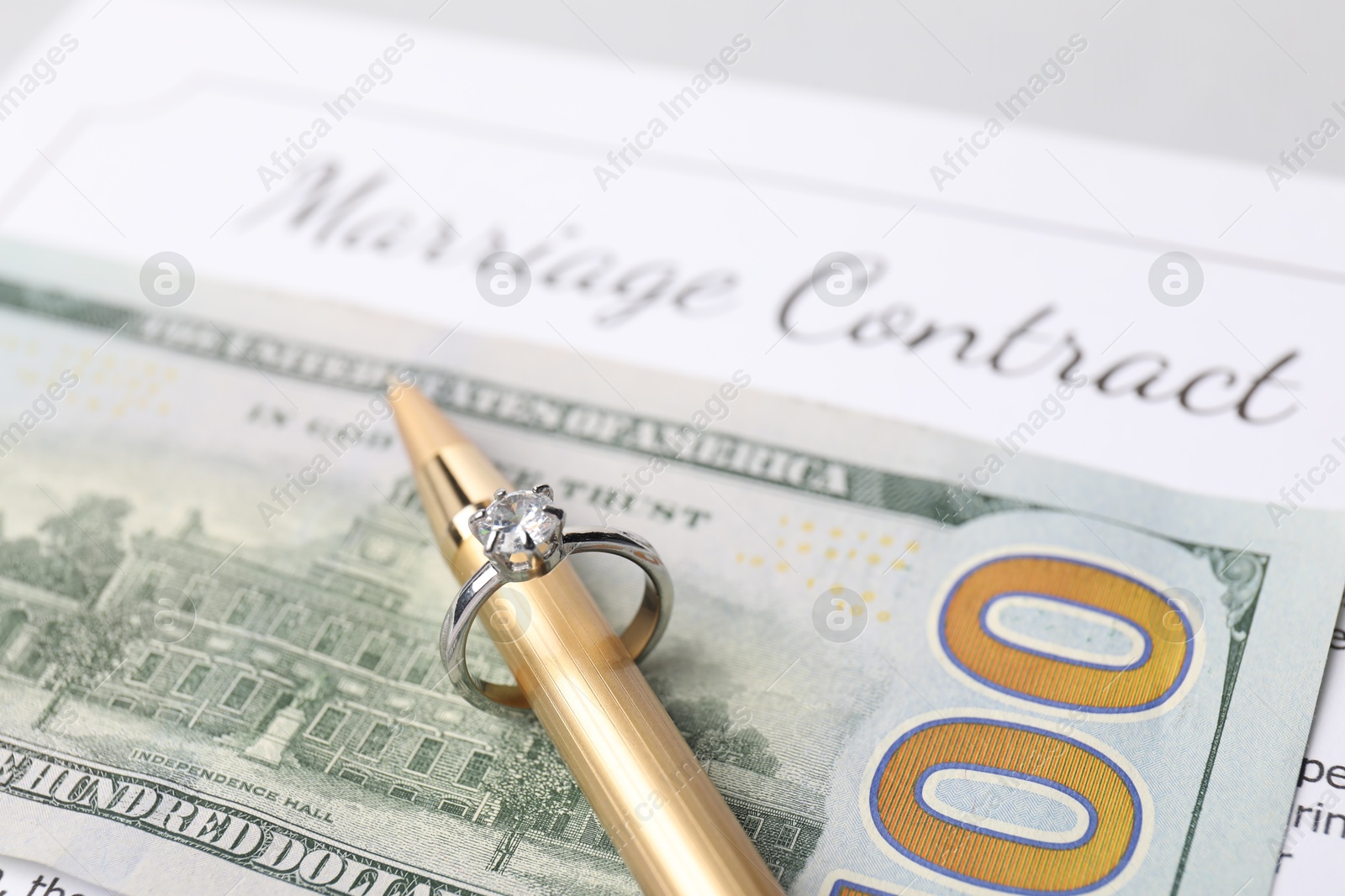 Photo of Marriage contract, pen with ring and dollar bill, closeup