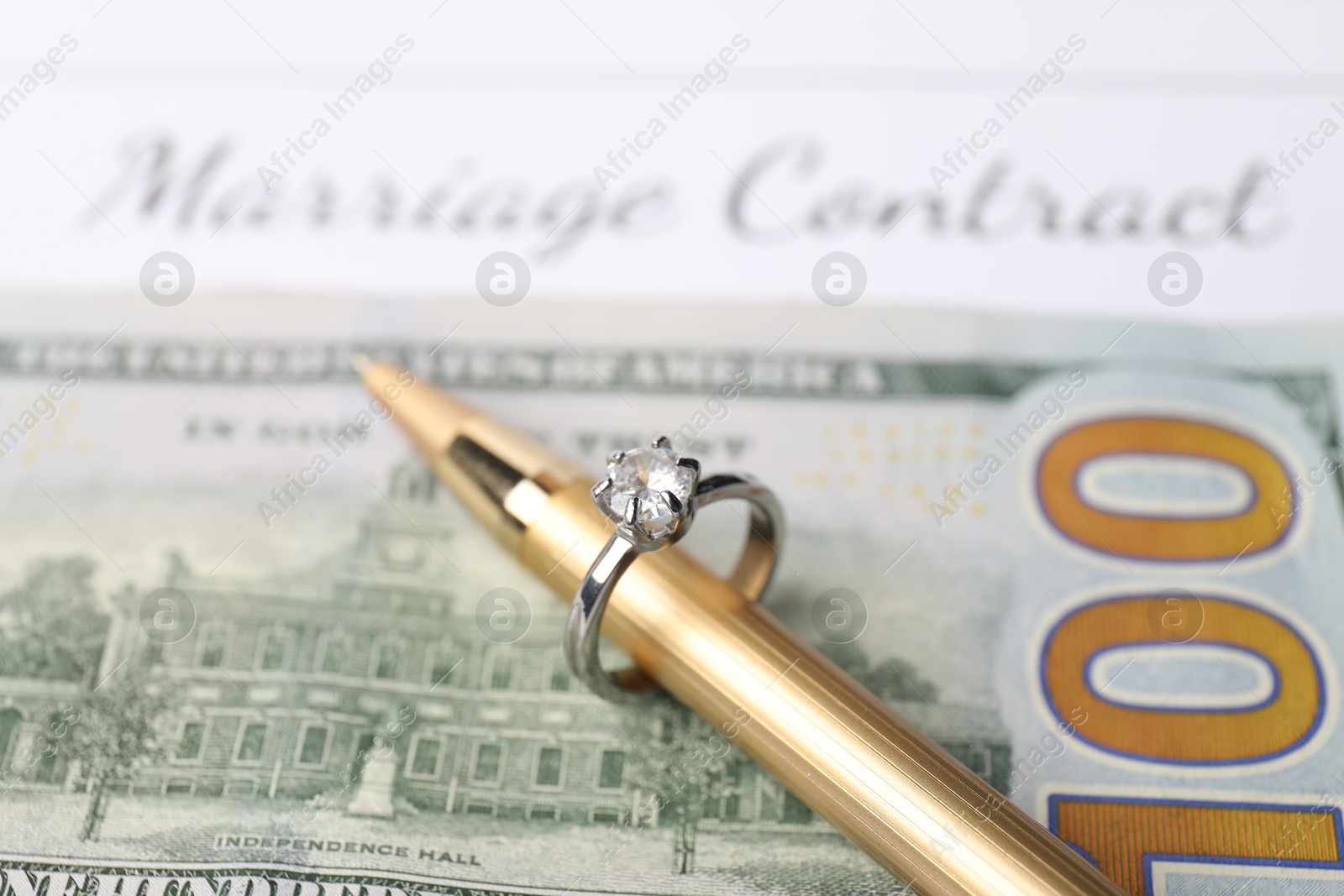 Photo of Marriage contract, pen with ring and dollar bill, closeup