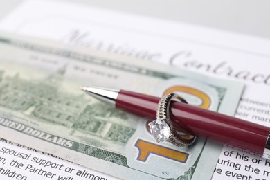 Photo of Marriage contract, pen with ring and dollar bill, closeup