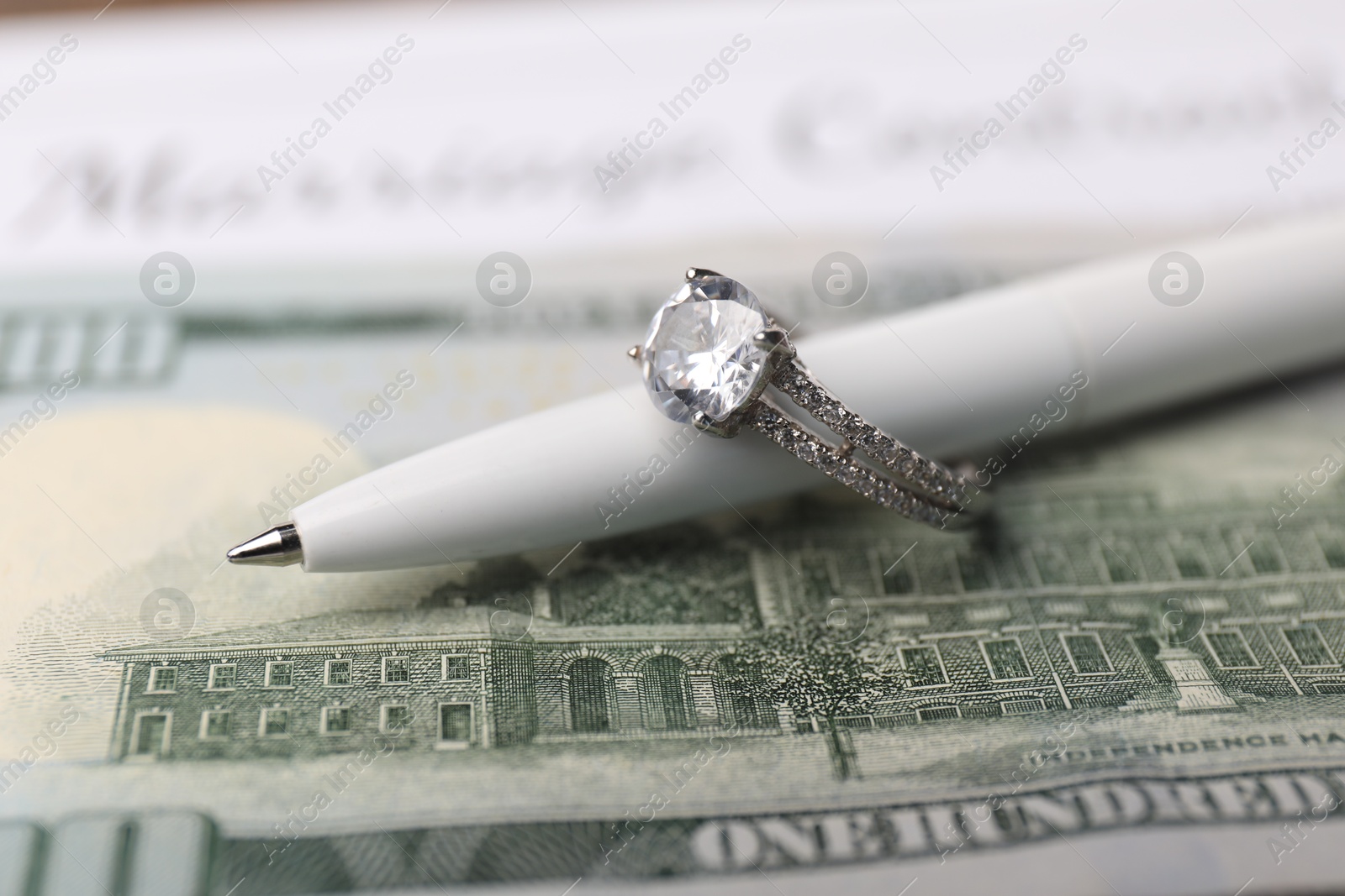 Photo of Marriage contract, dollar bill, pen and ring, closeup