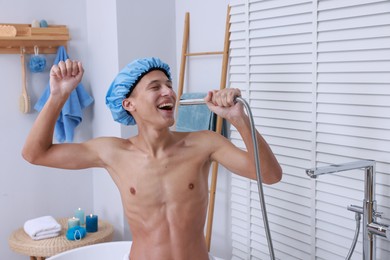 Photo of Man with cap singing while taking shower in bathroom