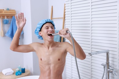 Man with cap singing while taking shower in bathroom