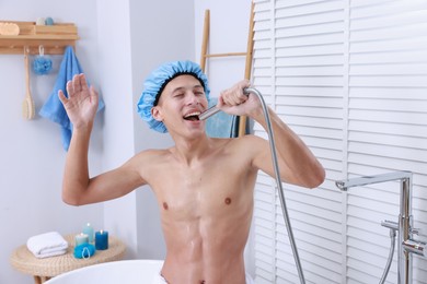 Photo of Man with cap singing while taking shower in bathroom