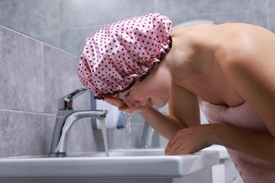 Woman with shower cap washing her face in bathroom