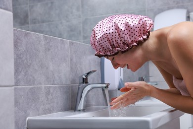 Photo of Woman with shower cap washing her face in bathroom