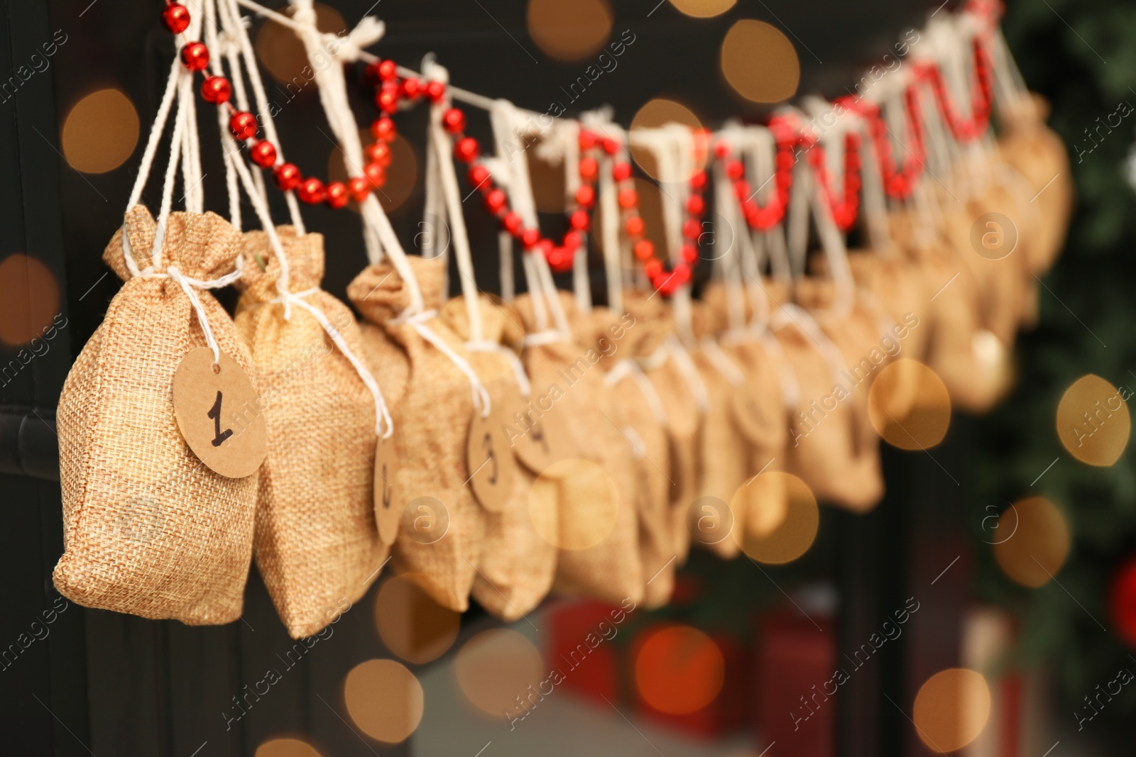 Photo of Christmas advent calendar with gifts and decor hanging on fireplace indoors, closeup. Space for text