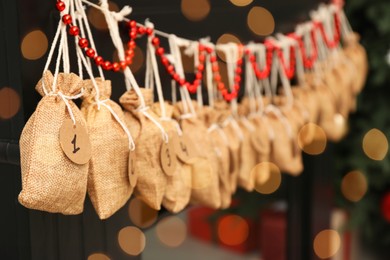 Photo of Christmas advent calendar with gifts and decor hanging on fireplace indoors, closeup. Space for text