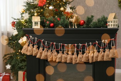 Photo of Christmas advent calendar with gifts and decor hanging on fireplace indoors