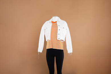 Female mannequin with stylish outfit on light brown background