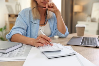 Photo of Budget planning. Woman using calculator at table indoors, closeup