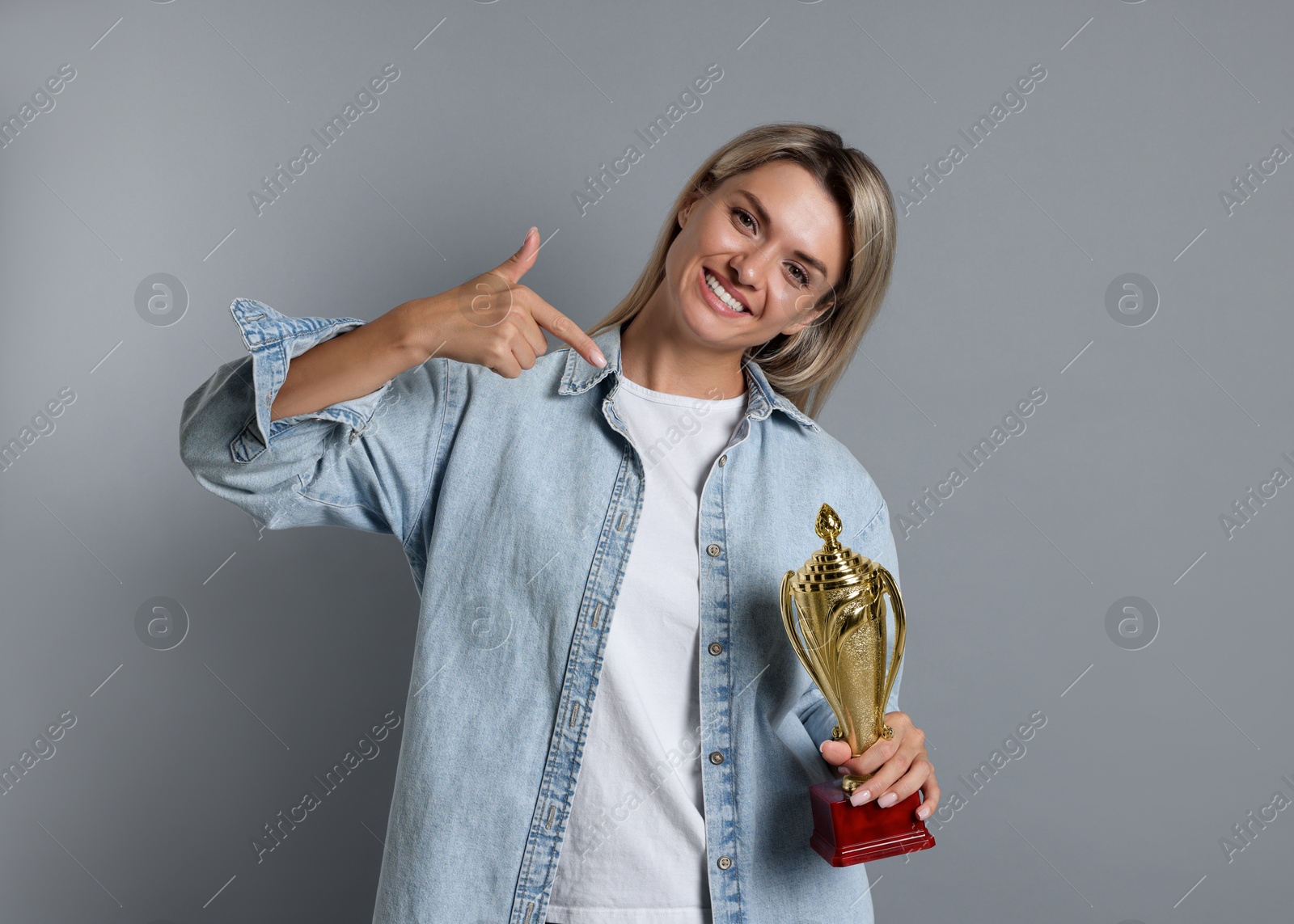 Photo of Happy winner with golden trophy cup on gray background