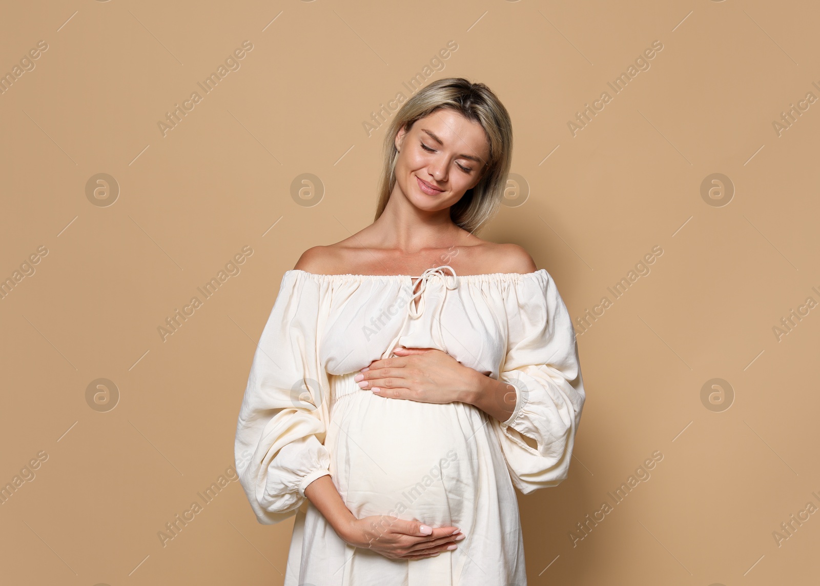 Photo of Portrait of beautiful pregnant woman on beige background