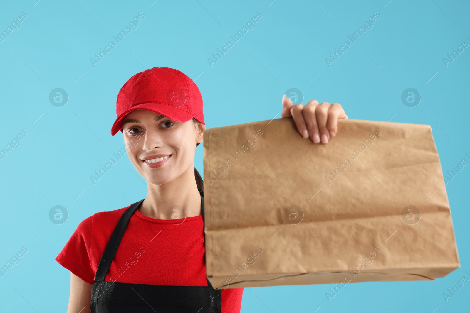 Photo of Fast-food worker with paper bag on light blue background