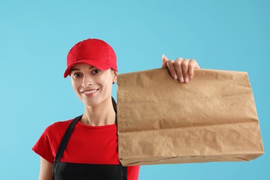 Fast-food worker with paper bag on light blue background