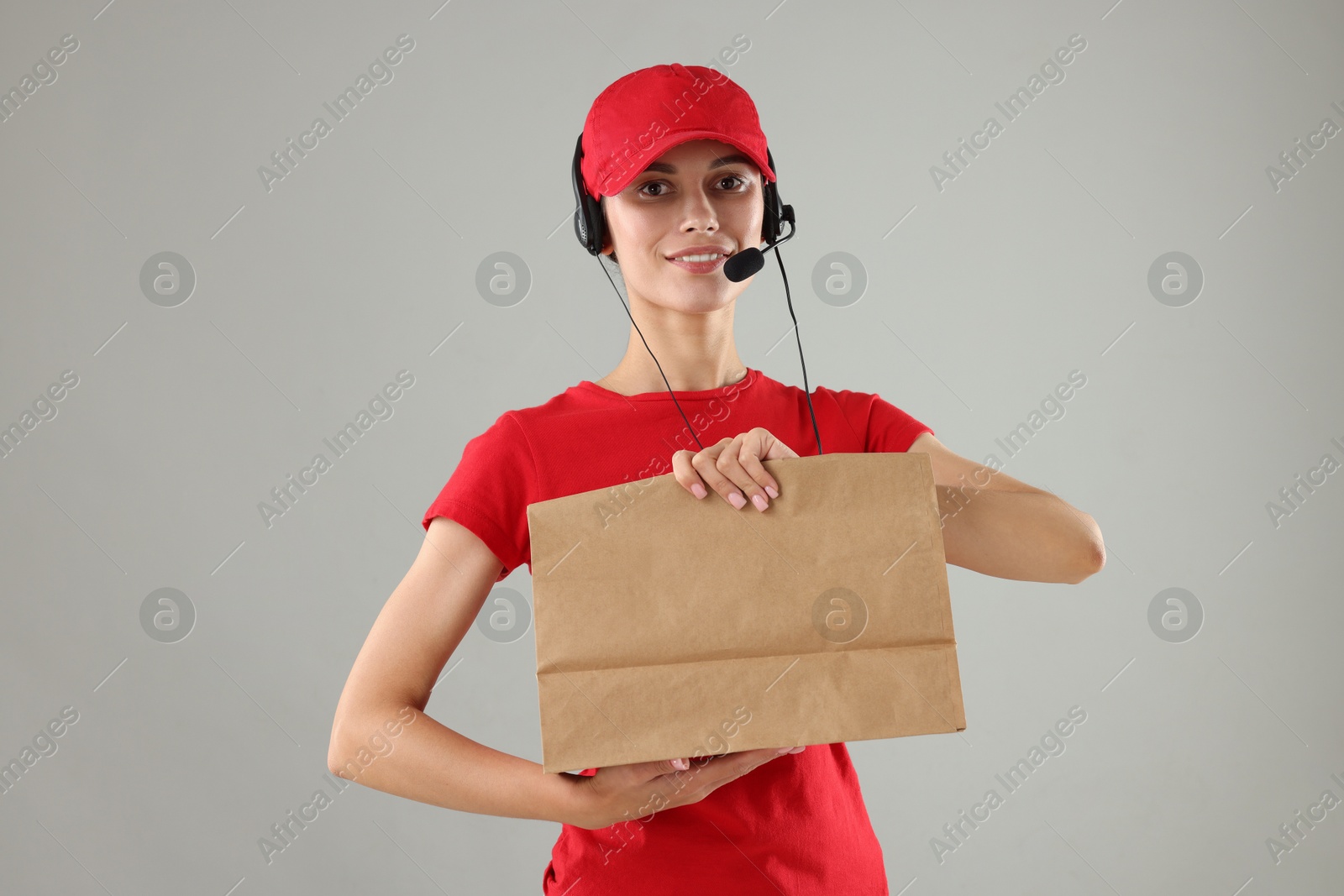 Photo of Fast-food worker with paper bag on gray background