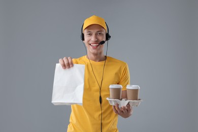 Photo of Fast-food worker with paper bag and cups on gray background