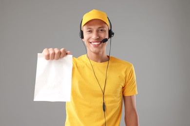 Photo of Fast-food worker with paper bag on gray background