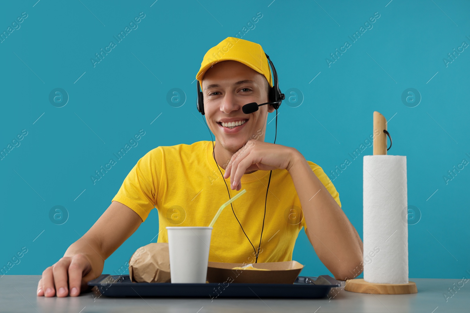 Photo of Fast-food worker with order at counter against light blue background