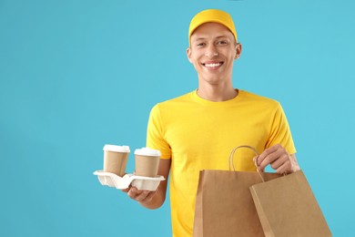 Photo of Fast-food worker with paper bags and cups on light blue background