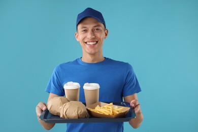 Photo of Fast-food worker holding tray with order on light blue background