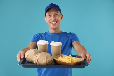 Photo of Fast-food worker holding tray with order on light blue background