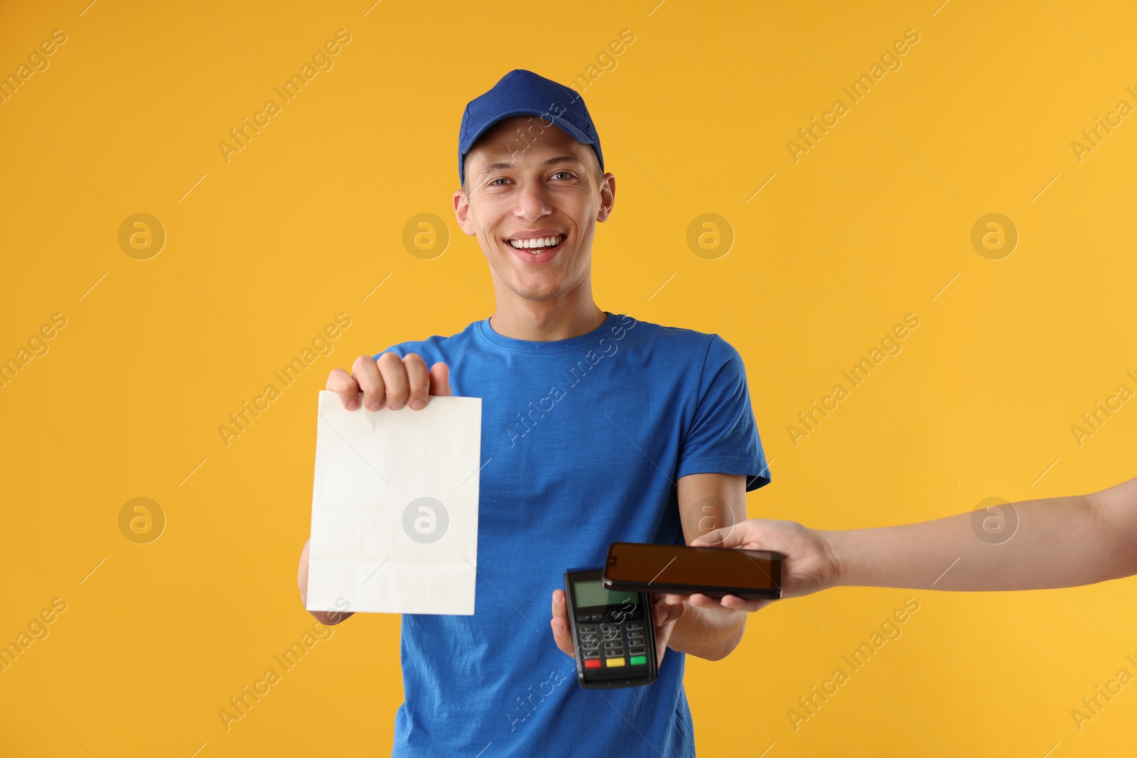 Photo of Fast-food worker taking payment from client via terminal on orange background, closeup