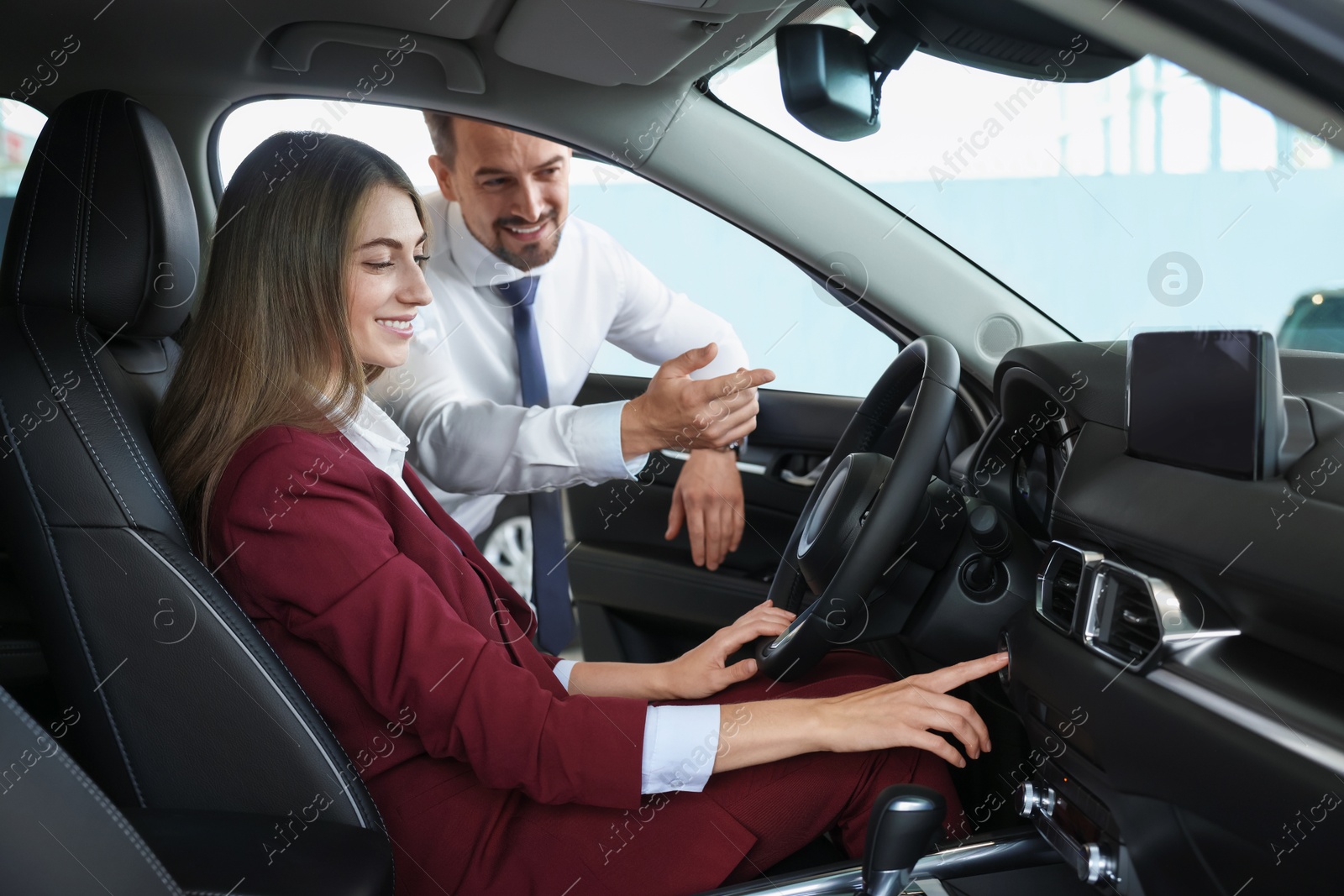 Photo of Happy salesman and client inside new car in salon