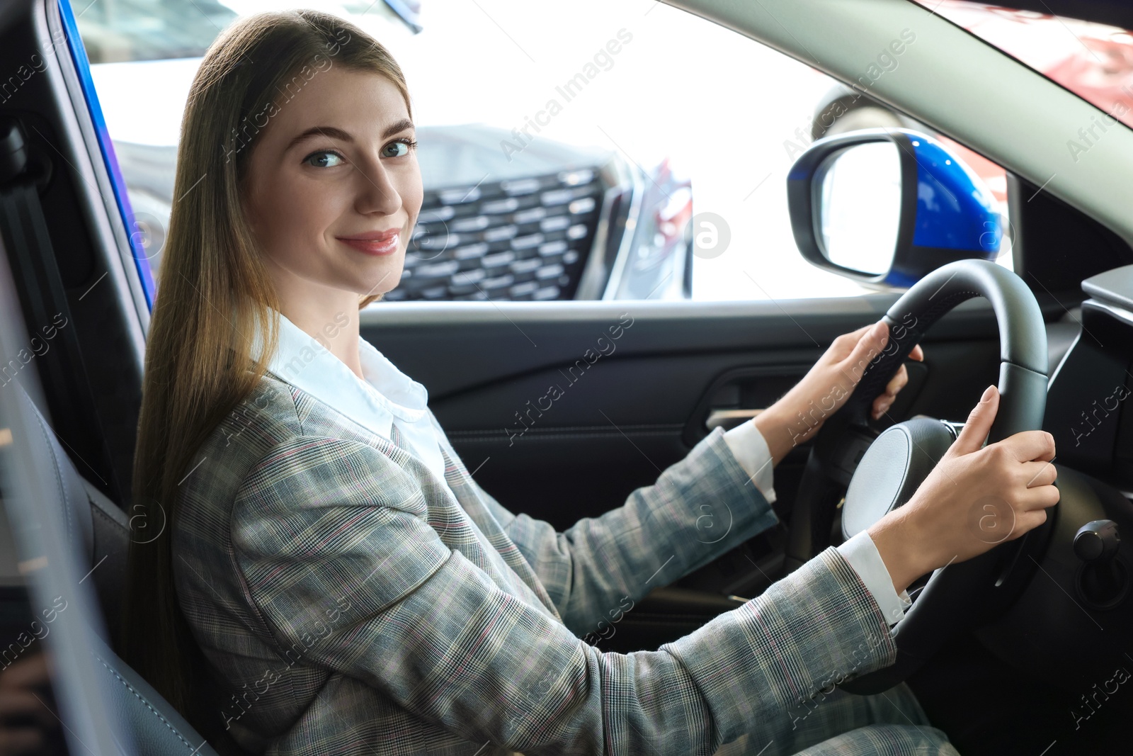 Photo of Young woman inside new car in salon