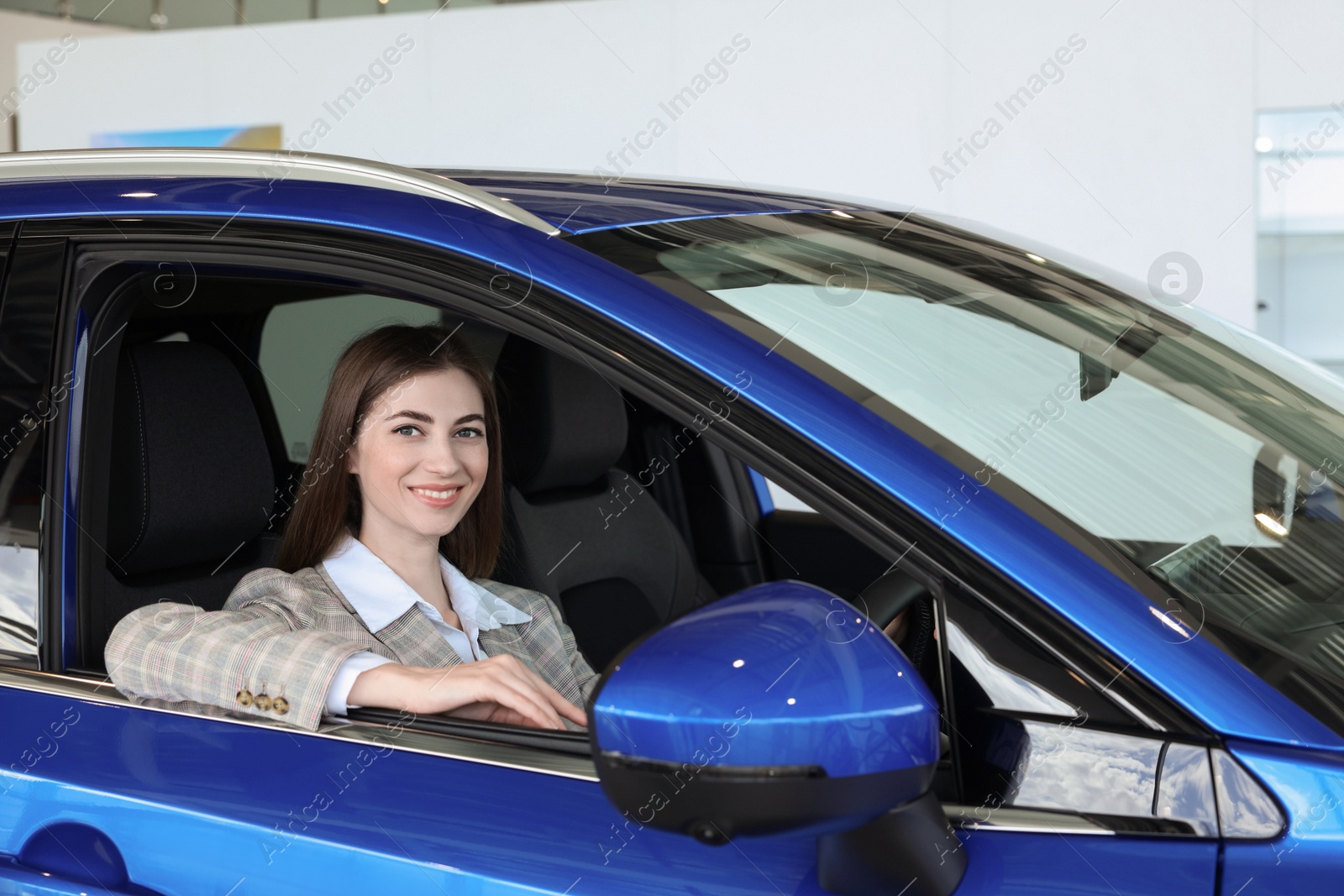 Photo of Young woman inside new blue car in salon