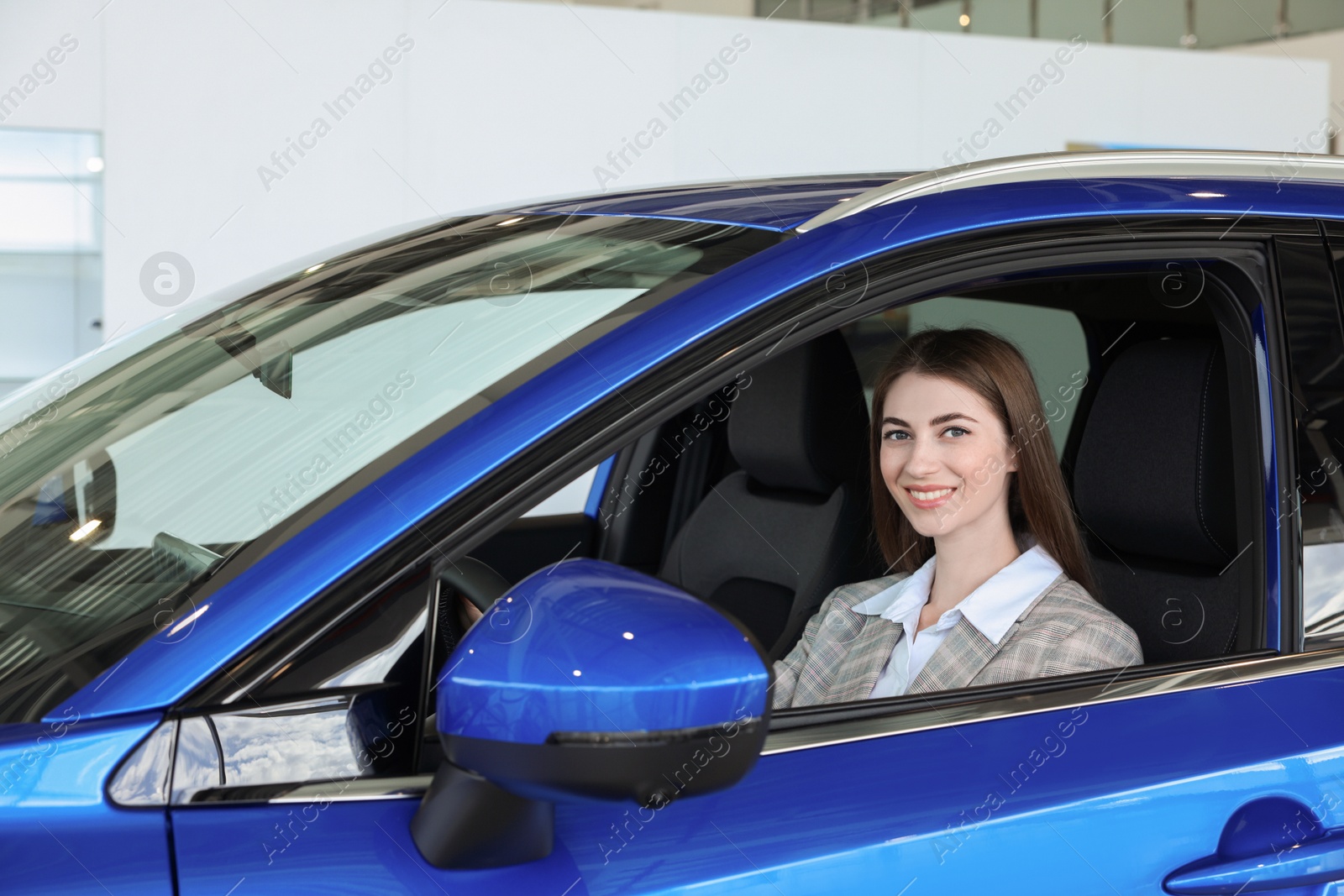 Photo of Young woman inside new blue car in salon