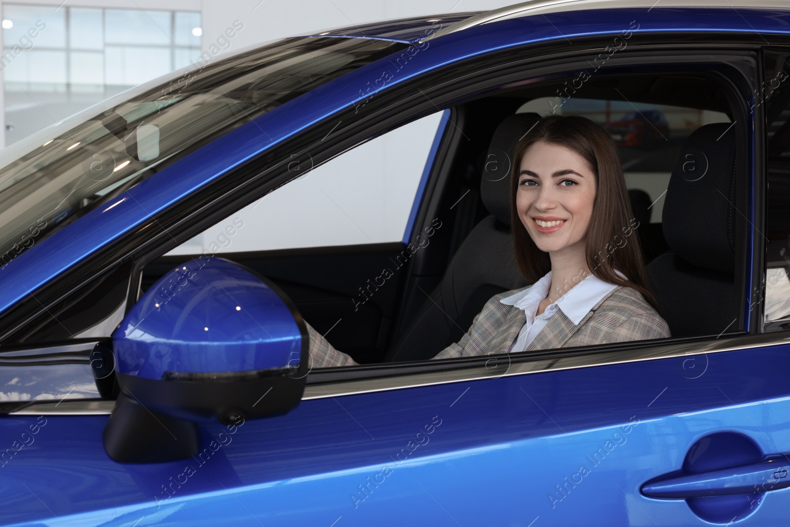 Photo of Young woman inside new blue car in salon