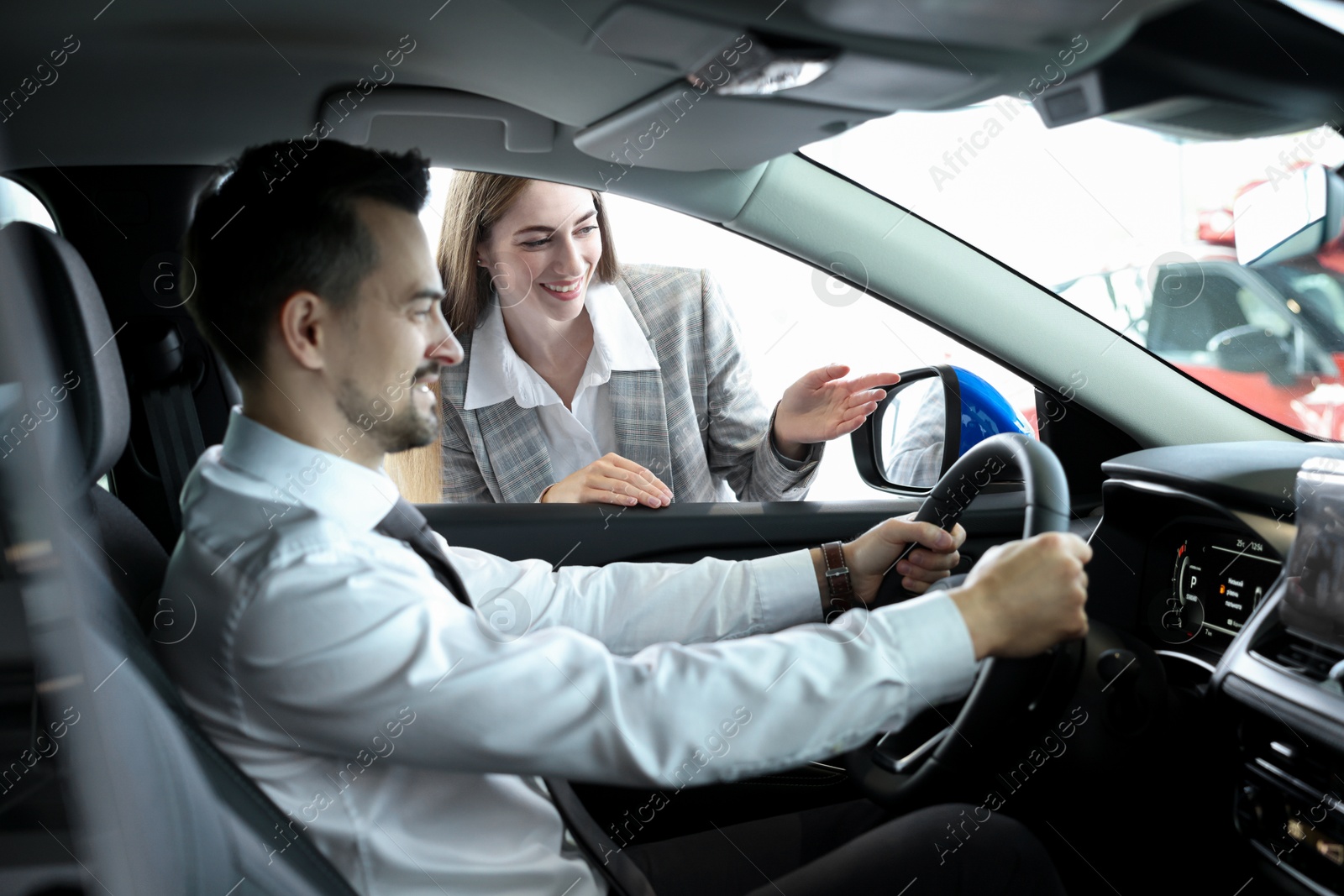 Photo of Saleswoman showing car to client in salon