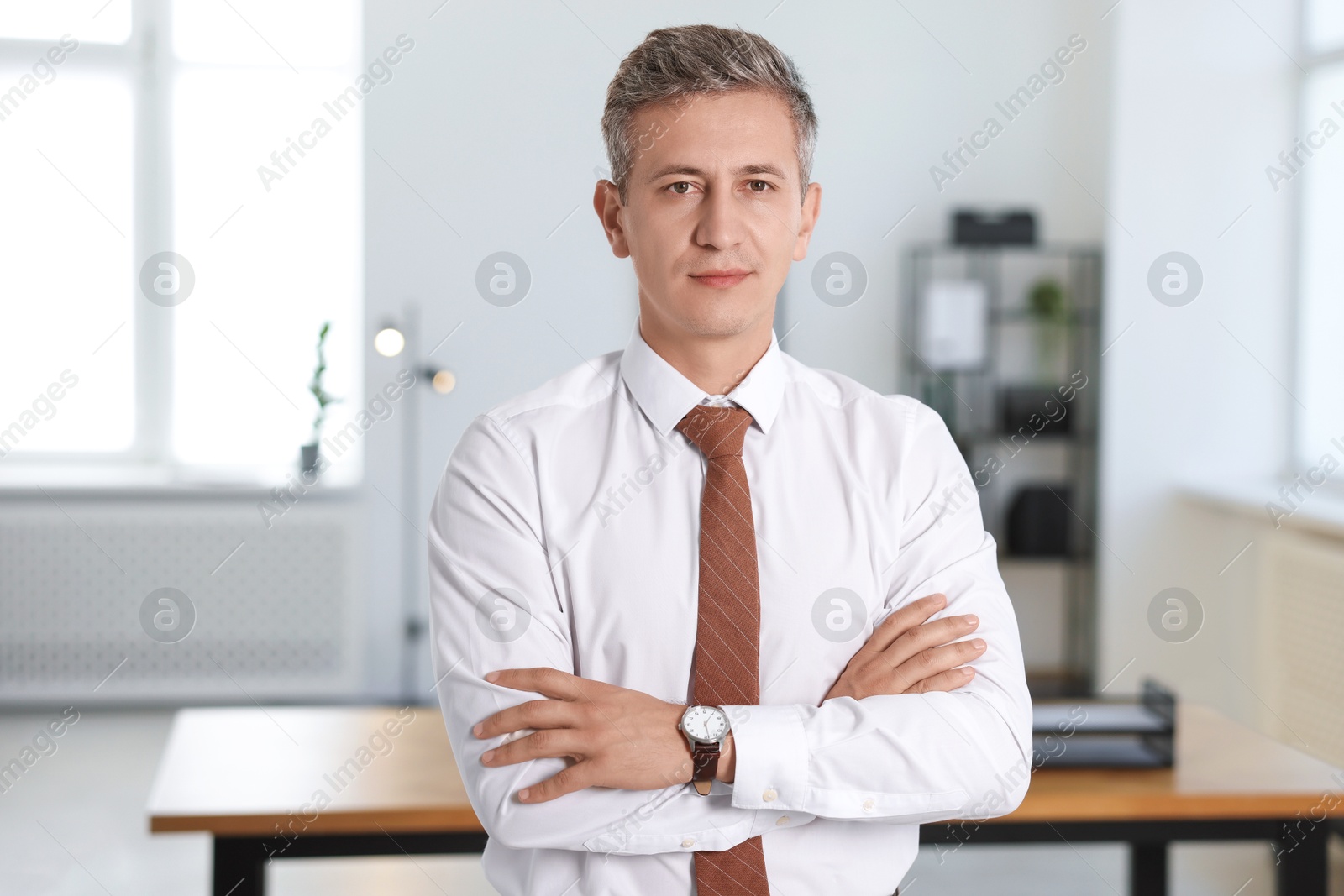 Photo of Portrait of middle aged man with crossed arms in office