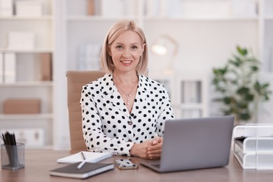 Photo of Portrait of smiling middle aged woman at table in office