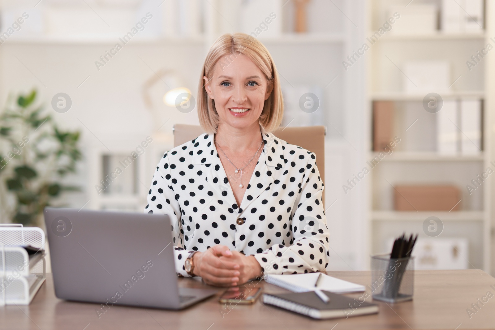 Photo of Portrait of smiling middle aged woman at table in office