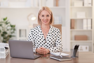 Photo of Portrait of smiling middle aged woman at table in office