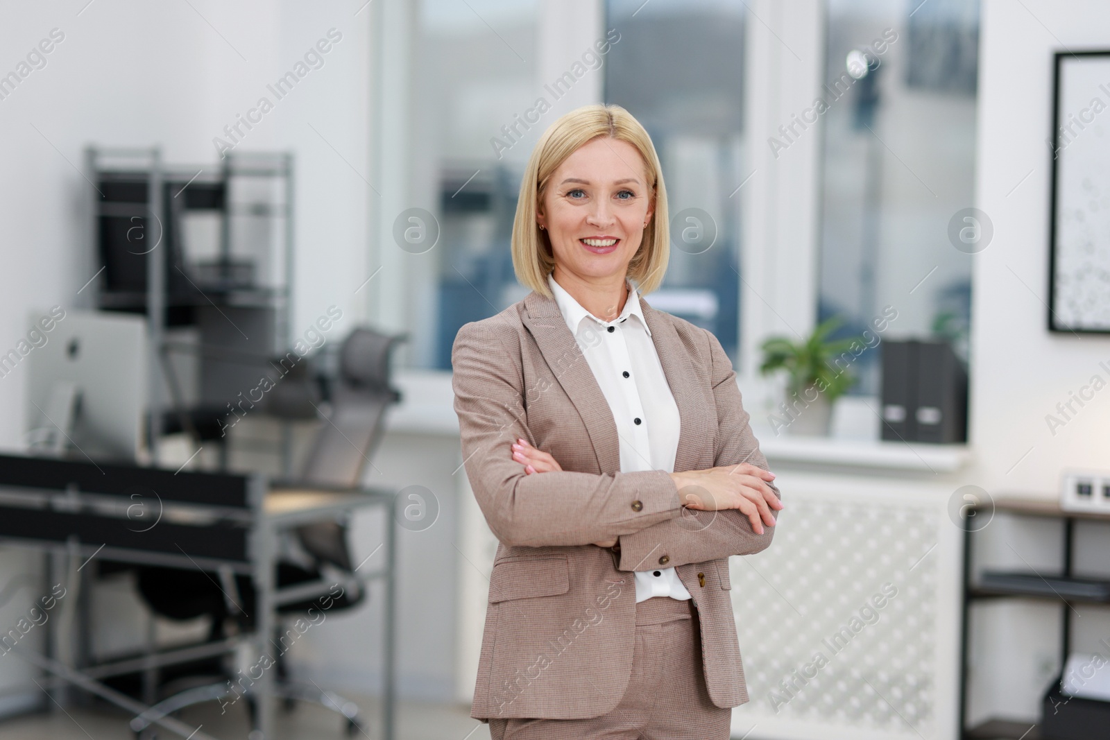 Photo of Portrait of smiling middle aged woman with crossed arms in office