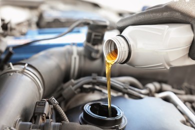 Photo of Man pouring motor oil into car engine, closeup