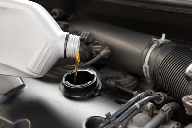 Photo of Pouring motor oil into car engine, closeup