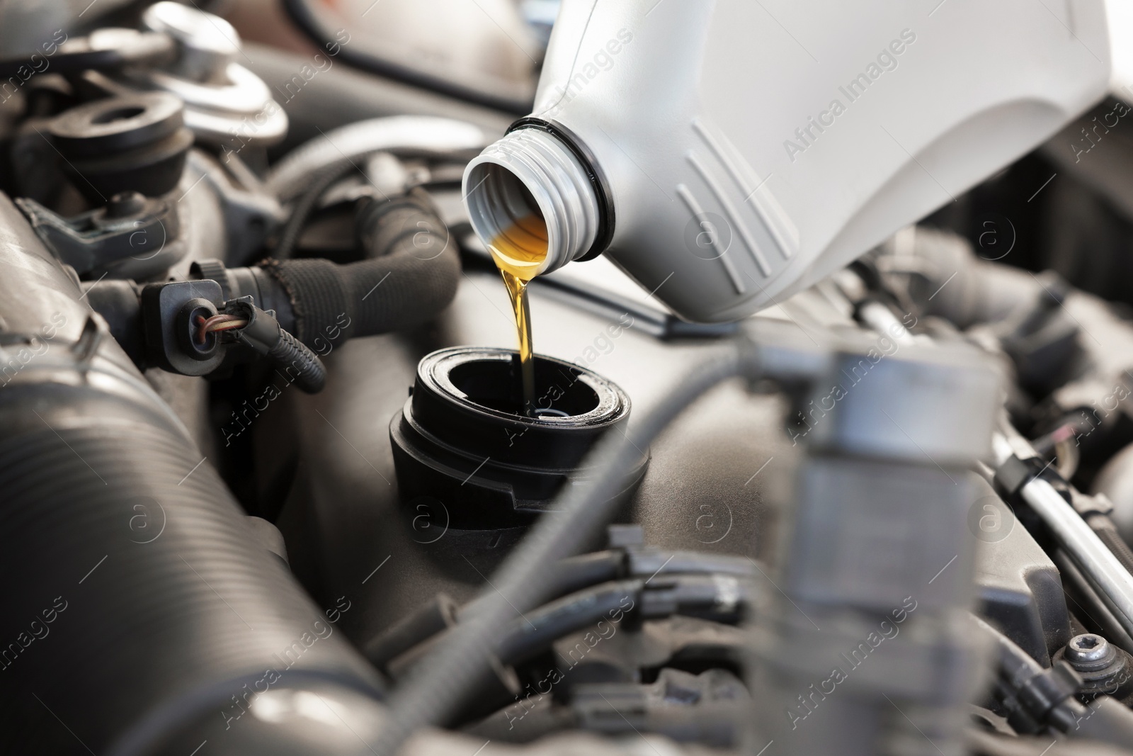 Photo of Pouring motor oil into car engine, closeup