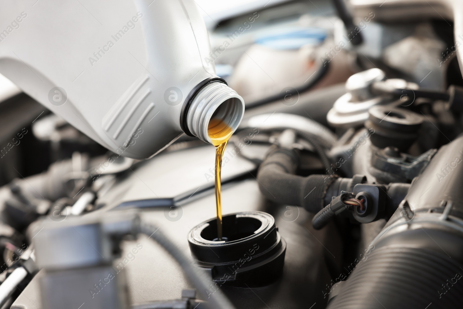 Photo of Pouring motor oil into car engine, closeup