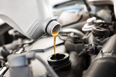 Photo of Pouring motor oil into car engine, closeup