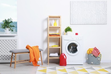 Photo of Washing machine, detergents and basket with laundry in room